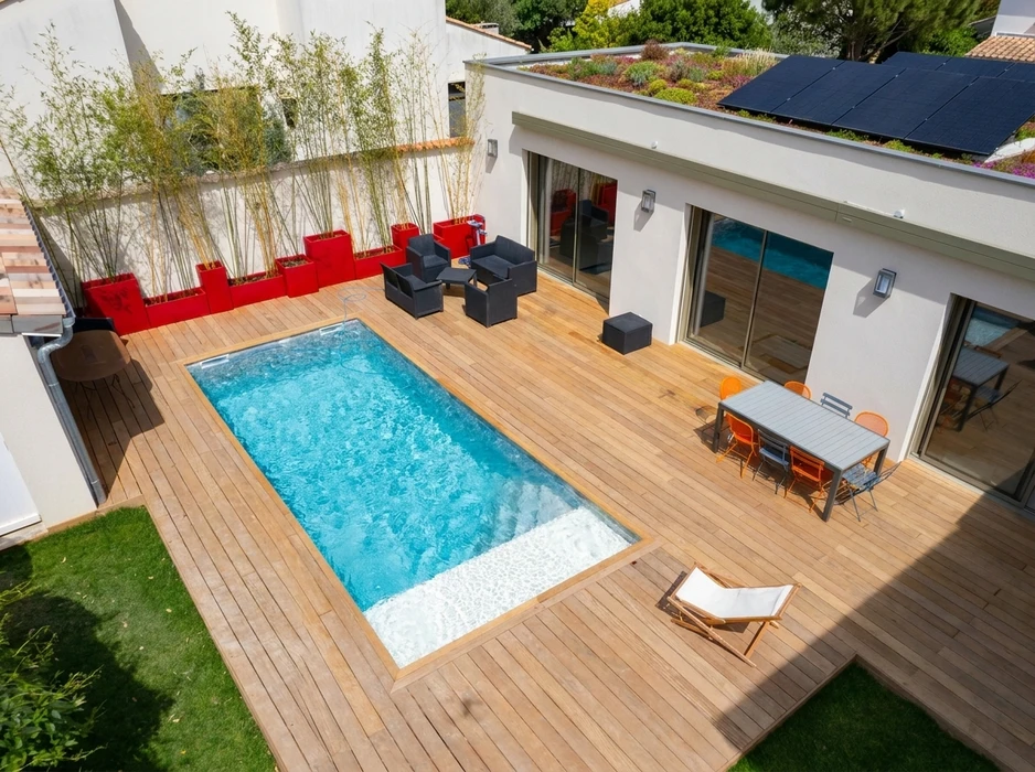 Piscine rectangulaire à débordement avec liner bleu turquoise, entourée d'une plage en dalles de pierre calcaire beige